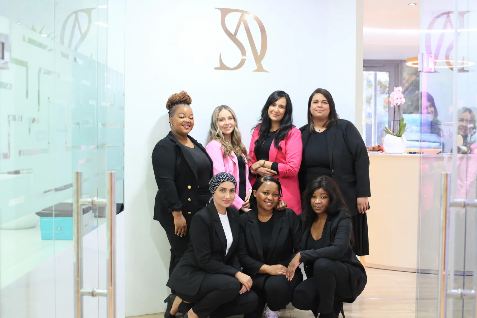 The Singh Advanced Dentistry team gathered at reception beneath the Singh logo