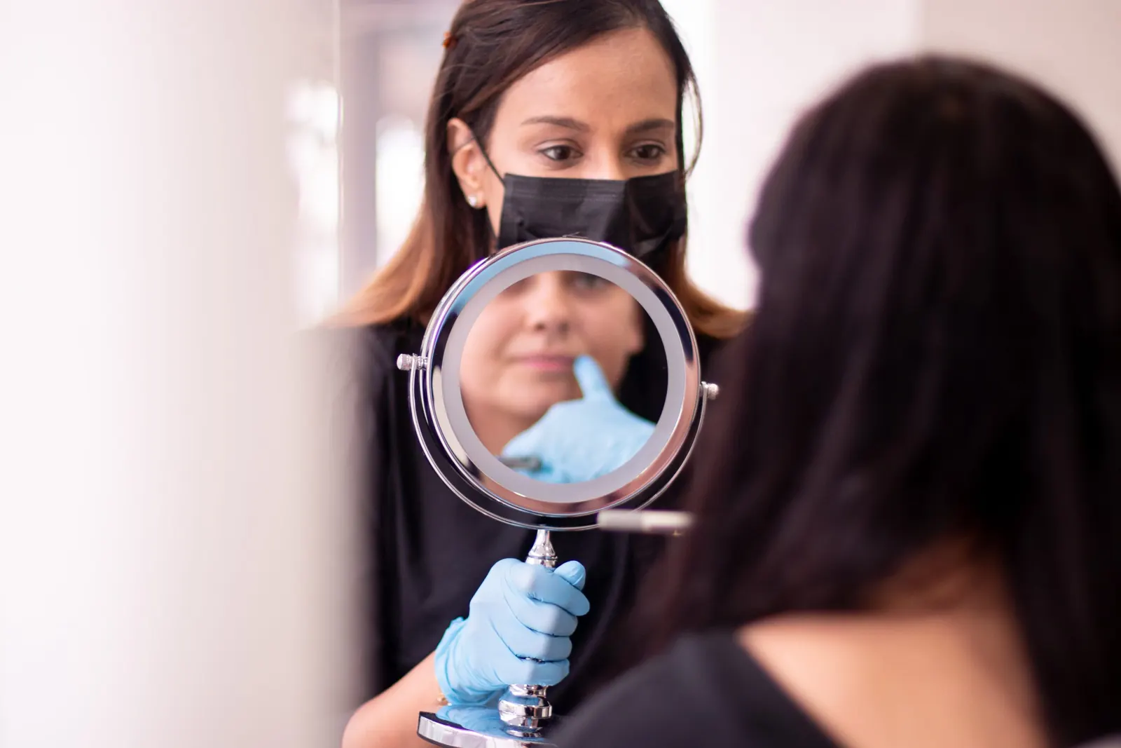 Dentist holding up a mirror while a patient checks her smile