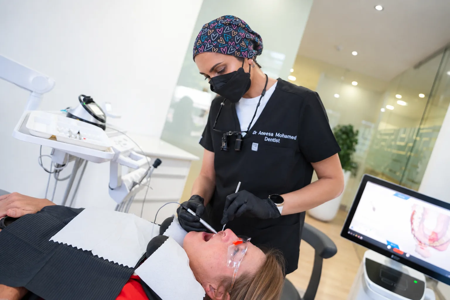 Dr Aneesa Mohamed treating a patient, with a 3D scan on the screen beside the chair