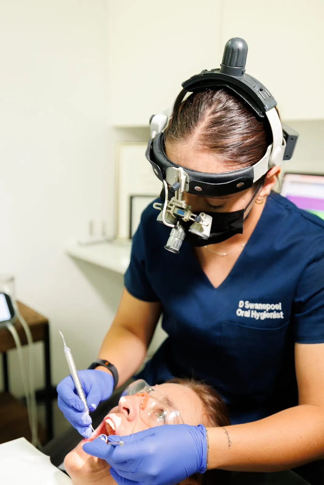 Oral hygienist treating a patient while wearing magnification loupes