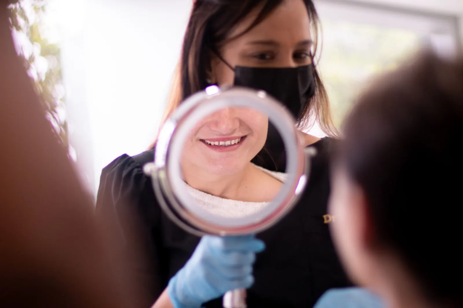 Patient smiling at her reflection in a hand mirror