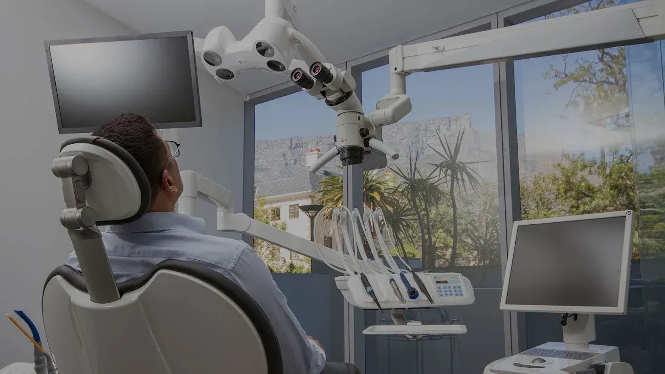 Patient reclining in a treatment chair facing a floor-to-ceiling window with a view of Table Mountain